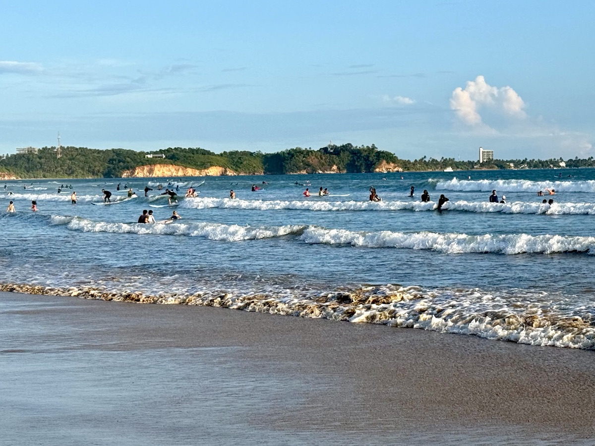 Surfers riding waves at Weligama Bay