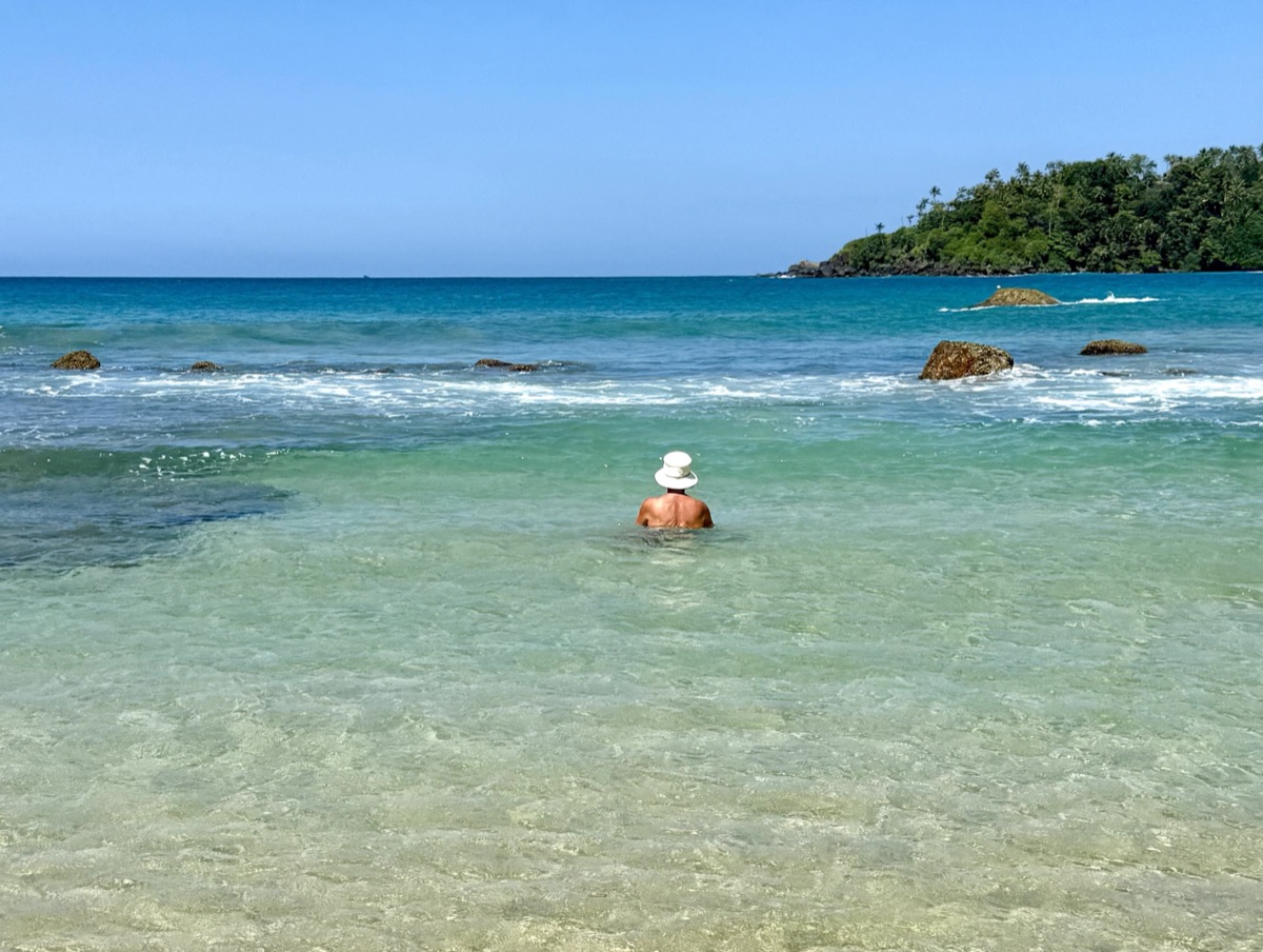 A swimmer in the clear turquoise water off Mirissa Beach
